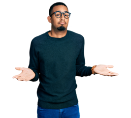 Young african american man wearing casual clothes and glasses clueless and confused expression with arms and hands raised. doubt concept.