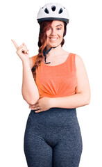 Young beautiful woman wearing bike helmet smiling happy pointing with hand and finger to the side