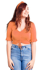 Young beautiful woman wearing casual clothes looking away to side with smile on face, natural expression. laughing confident.