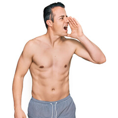 Fototapeta premium Handsome young man wearing swimwear shirtless shouting and screaming loud to side with hand on mouth. communication concept.