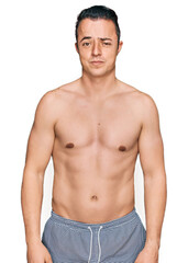 Fototapeta premium Handsome young man wearing swimwear shirtless skeptic and nervous, frowning upset because of problem. negative person.