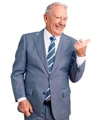 Senior handsome grey-haired man wearing elegant suit smiling with happy face looking and pointing to the side with thumb up.