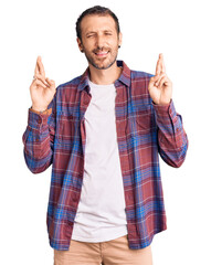 Naklejka premium Young handsome man wearing casual clothes gesturing finger crossed smiling with hope and eyes closed. luck and superstitious concept.