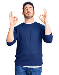 Fototapeta premium Young hispanic man wearing casual clothes relax and smiling with eyes closed doing meditation gesture with fingers. yoga concept.