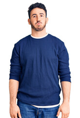 Fototapeta premium Young hispanic man wearing casual clothes puffing cheeks with funny face. mouth inflated with air, crazy expression.