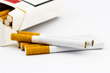 Group of cigarettes lying near the box full of cigarettes isolated on white background