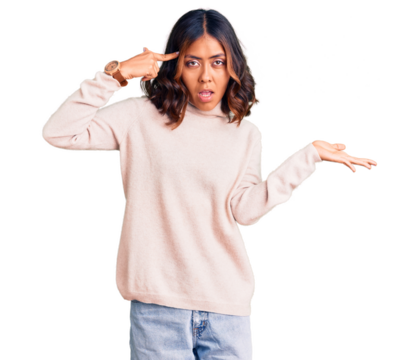 Young beautiful mixed race woman wearing winter turtleneck sweater confused and annoyed with open palm showing copy space and pointing finger to forehead. think about it.