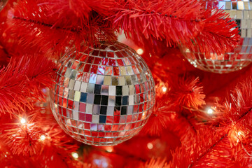 Silver disco ball on a red christmas tree. Festive new year background.