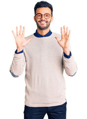 Young handsome hispanic man wearing elegant clothes and glasses showing and pointing up with fingers number ten while smiling confident and happy.