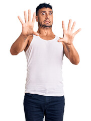 Young hispanic man wearing casual clothes afraid and terrified with fear expression stop gesture with hands, shouting in shock. panic concept.