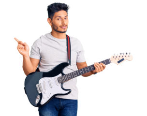 Handsome latin american young man playing electric guitar smiling happy pointing with hand and finger to the side