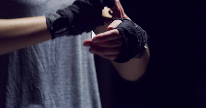 Fitness, boxing and training by athlete prepare for exercise, wrap hands against a black background. Boxer getting ready for a speed and endurance performance at gym, tough physical strength match