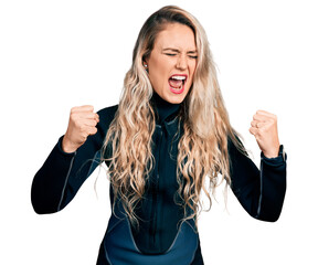 Young blonde woman wearing diver neoprene uniform angry and mad raising fists frustrated and...