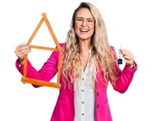 Young blonde woman holding keys of new home and build project smiling and laughing hard out loud because funny crazy joke.