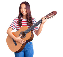 Young beautiful chinese girl playing classical guitar looking positive and happy standing and smiling with a confident smile showing teeth