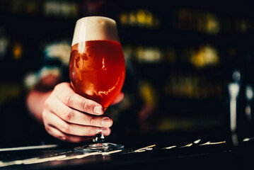 Fototapeta na wymiar bartender's hand hold full glass of beer in a bar
