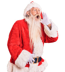 Old senior man with grey hair and long beard wearing traditional santa claus costume shouting and screaming loud to side with hand on mouth. communication concept.
