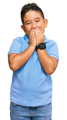 Little boy hispanic kid wearing casual clothes laughing and embarrassed giggle covering mouth with...