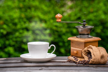 coffee cup with a grinder, Dark Coffee beans on the old wooden floor,  Close up of seeds of coffee in a natural background.