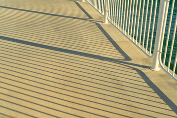 Long evening shadows from the railing on the pier.