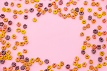 children's dry breakfast multicolored rings on a pink background, next to the place under the text