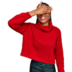 African american woman wearing casual winter sweater smiling and laughing with hand on face covering eyes for surprise. blind concept.