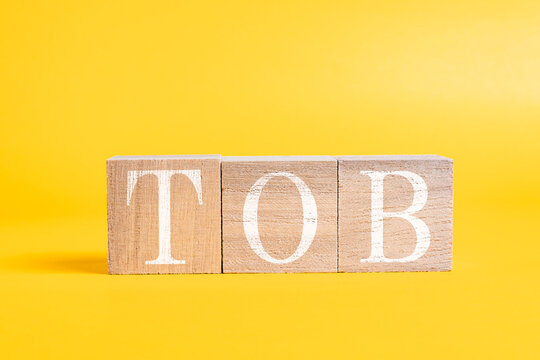 A technical term of TOB on wooden cubes on yellow background, Take Over Bid, Finance or stock background, Economy