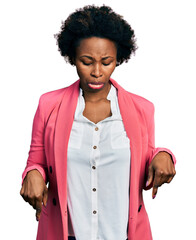 African american woman with afro hair wearing business jacket pointing down looking sad and upset,...