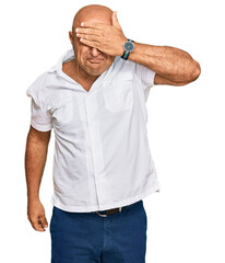 Mature middle east man with mustache wearing casual white shirt covering eyes with hand, looking serious and sad. sightless, hiding and rejection concept