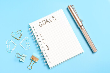 The inscription goals on notepad on blue background, copy space.