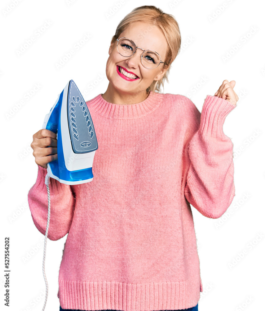 Canvas Prints Young blonde woman holding electric steam iron screaming proud, celebrating victory and success very excited with raised arm