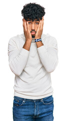 Young arab man wearing casual winter sweater tired hands covering face, depression and sadness,...