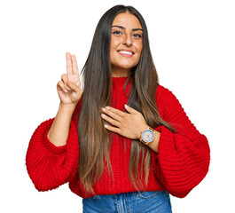 Beautiful hispanic woman wearing casual clothes smiling swearing with hand on chest and fingers up,...