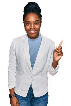 Young african american woman wearing business clothes with a big smile on face, pointing with hand finger to the side looking at the camera.