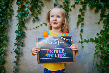 Cheerful 3 years old girl holding a poster with text 
