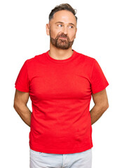 Handsome middle age man wearing casual red tshirt smiling looking to the side and staring away thinking.