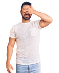 Fototapeta premium Young hispanic man wearing casual clothes smiling and laughing with hand on face covering eyes for surprise. blind concept.