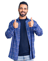 Young hispanic man wearing casual clothes success sign doing positive gesture with hand, thumbs up...