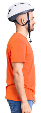 Young handsome man wearing bike helmet looking to side, relax profile pose with natural face with confident smile.