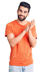 Young handsome man with beard wearing casual t-shirt clapping and applauding happy and joyful, smiling proud hands together