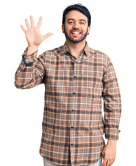 Young hispanic man wearing casual clothes showing and pointing up with fingers number five while...