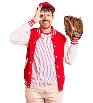 Young handsome man with curly hair wearing baseball uniform holding golve and ball smiling happy doing ok sign with hand on eye looking through fingers