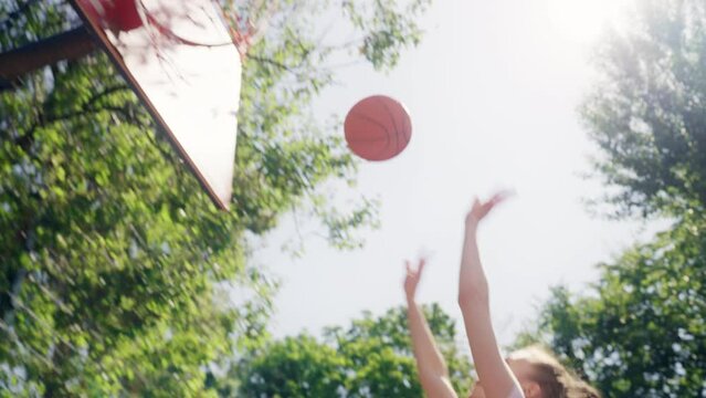 Confident young lady in motion scoring points while playing basketball, slowmo