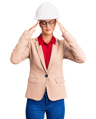 Young beautiful woman wearing architect hardhat suffering from headache desperate and stressed because pain and migraine. hands on head.