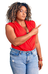 Young african american plus size woman wearing casual style with sleeveless shirt pointing with hand finger to the side showing advertisement, serious and calm face