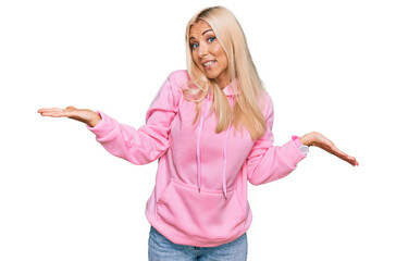 Fototapeta premium Young blonde woman wearing casual sweatshirt smiling showing both hands open palms, presenting and advertising comparison and balance