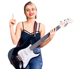 Fototapeta premium Young beautiful blonde woman playing electric guitar surprised with an idea or question pointing finger with happy face, number one