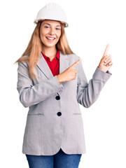 Beautiful young woman wearing architect hardhat smiling and looking at the camera pointing with two hands and fingers to the side.