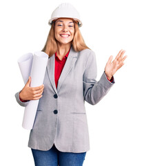 Beautiful young woman wearing architect hardhat holding build project celebrating victory with happy smile and winner expression with raised hands