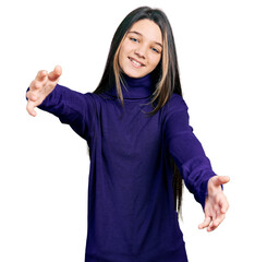 Young brunette girl with long hair wearing turtleneck sweater looking at the camera smiling with open arms for hug. cheerful expression embracing happiness.